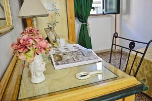 a glass table with a vase with flowers and a magazine at Hotel Victoria in Taormina