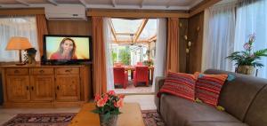sala de estar con sofá y TV de pantalla plana en Knus chalet midden in de natuur en de rust., en Wageningen