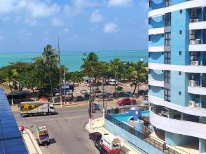 - une vue sur une rue avec un bâtiment et un parking dans l'établissement NA BEIRA MAR DE PAJUCARA- EDIF NEO- APARTAMENTO QUARTO E SALA- TEM VARANDA - VISTA LATERAL DO MAR- RUA JULIO PLECH FILHO 60 ESQUINA COM AVENIDA DOUTOR ANTONIO GOUVEIA - CONSUMO ELETRICO É PAGO No CKECK-OUT 1KWH É 1,35 REIAS, à Maceió