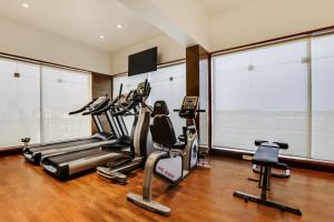 a gym with three tread machines in a room with large windows at Lemon Tree Hotel Viman Nagar Pune in Pune