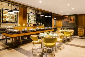 a restaurant with tables and chairs and a bar at Lemon Tree Hotel Viman Nagar Pune in Pune