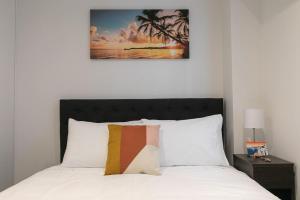 ein Schlafzimmer mit einem Bett mit einem Bild an der Wand in der Unterkunft 2BR Apartment w/ Balcony, Gym and Parking Access! in Auckland