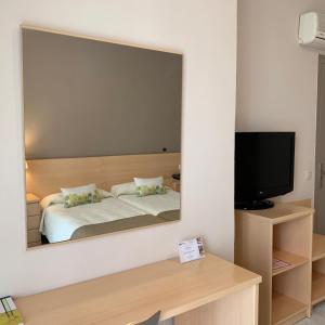 espejo que refleja un dormitorio con cama y TV en Hotel Restaurant Llansola, en Sant Carles de la Ràpita