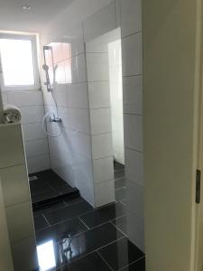 a bathroom with a shower with a black tile floor at Hotel Restaurant Memo in Mannheim