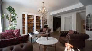 a living room with leather furniture and a chandelier at Hotel Passport Tbilisi in Tbilisi City