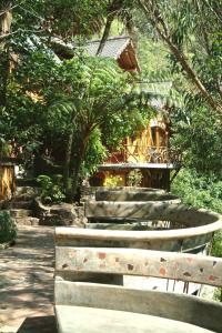 
a park with trees and benches and a waterfall at Finca Chamanapamba Guest House in Baños
