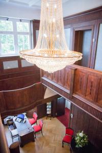 a large chandelier hanging in a room with red chairs at Pension Villa-Ingeborg in Fürstenberg