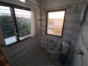 La salle de bains est pourvue de toilettes et de 2 fenêtres. dans l'établissement บ้านพรศรี Homestay, à Loei