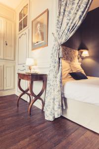 a bedroom with a bed and a table with a curtain at La Maison de la Liberté Jean-François de La Pérouse in Poitiers