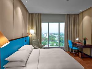 德里久尔Hyatt Regency Thrissur的配有一张大床和一张书桌的酒店房间