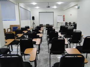 une salle de classe vide avec des bureaux, des chaises et un tableau blanc dans l'établissement Hotel Flor de Minas, à Uberaba