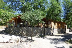 Cabaña de madera con pared de piedra y árboles en Rev'ôthijol Vacances, en Auriolles