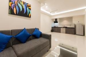 a living room with a couch with blue pillows at Manipal Atalia Service Apartments in Manipala