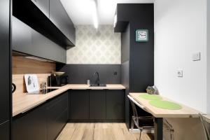 a kitchen with black cabinets and a sink and a table at Krupnicza Premium Apartments in Krakow