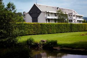 a building sitting on top of a field next to a river at Premiere Classe Creil - Villers Saint Paul in Villers-Saint-Paul