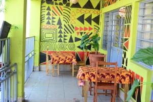 patio ze stołami i krzesłami oraz malowidłem ściennym w obiekcie MUHABURA MOUNTAIN LODGE w mieście Gisenyi