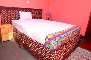 - une chambre avec un grand lit dans une pièce avec une table dans l'établissement MUHABURA MOUNTAIN LODGE, à Gisenyi