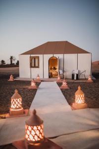a tent in the middle of a field with lights at Riad Kasbah Aiour in Merzouga