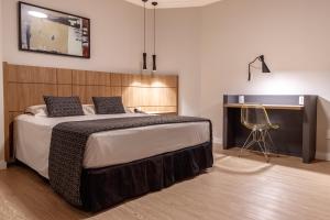 a bedroom with a bed with a desk and a chair at Mara Turismo Hotel in Catalão