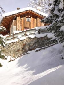 una cabina ricoperta di neve con un muro di pietra di BAITA BEDOLINA a Temù
