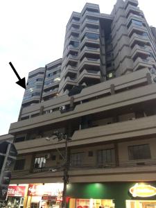 un edificio alto con una tienda delante en LINDO APARTAMENTO EM MEIA PRAIA-1 quadra do mar! Melhor localização!, en Itapema