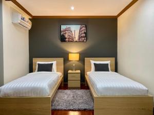 a bedroom with two beds and a tv on the wall at NT Place Sukhumvit Suites in Bangkok