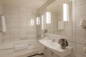biała łazienka z umywalką i wanną w obiekcie National Hotel w Kłajpedzie