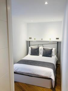 a bedroom with a large white bed with two pillows at Luxe Holiday Rentals in Gibraltar