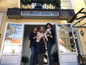 three women standing in front of a door with a dog at Hotel Jäger - family tradition since 1911 in Vienna