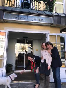 ウィーンにあるHotel Jäger - family tradition since 1911の犬と一緒に店の前でポーズをとった三人