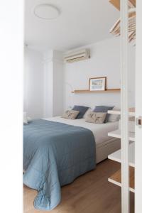 een witte slaapkamer met een bed met een blauwe deken bij FLORIT FLATS - Apartment Torres de Quart II in Valencia