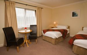 Cette chambre comprend deux lits, une table et une fenêtre. dans l'établissement Renvyle House Hotel & Resort, à Renvyle