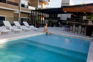 una mujer sentada en el borde de una piscina en Hotel Puesta del Sol, en Encarnación