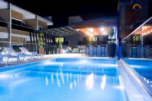 una piscina por la noche con sillas y un bar en Hotel Puesta del Sol, en Encarnación