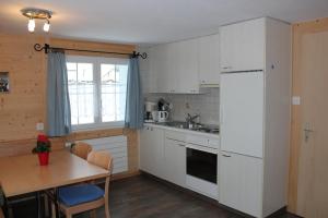 a kitchen with a table and a white refrigerator at Chalet Good in Flumserberg