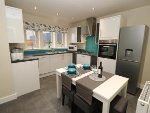 una cocina con armarios blancos y una mesa con platos azules. en Modern Town House Shepley, en Huddersfield