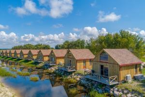 a row of cottages in a row on a river at Drevernos kempingas in Dreverna
