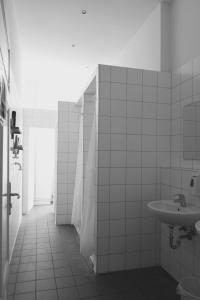 a white tiled bathroom with a sink and a shower at 36 Rooms Hostel Berlin Kreuzberg in Berlin
