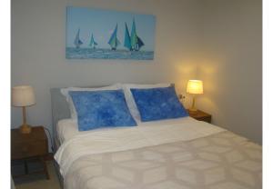 un lit avec des oreillers bleus et un tableau de voiliers dans l'établissement Althea's stylish,homely apartment on the beach by Althea Holidays - AH 7, à Grand Baie 25 autres photos
