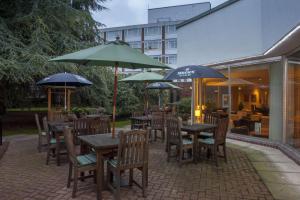 eine Terrasse mit Tischen, Stühlen und Sonnenschirmen in der Unterkunft Holiday Inn York, an IHG Hotel in York