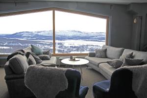 a living room with couches and a large window at Hemavans Högfjällshotell in Hemavan