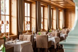 uma sala de jantar com mesas, cadeiras e janelas em Schlosshotel Fiss em Fiss