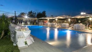 a pool with white tables and chairs at night at Agriturismo Torre Flavia in Ladispoli