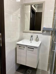 a white bathroom with a sink and a mirror at Apartman I&M in Ston