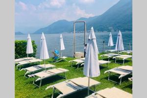 a group of lounge chairs and umbrellas next to the water at Argegno Penthouse in Argegno
