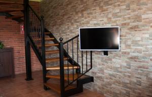 a television hanging on a brick wall with a staircase at Apartamento Vega Rodiles El Valle in Villaviciosa