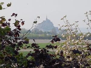 a field with a castle in the background with a tree at Le Goeland in Beauvoir