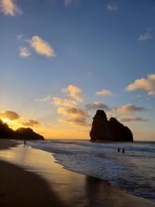 a group of people walking on the beach at sunset at Suíte Abreu Noronha in Fernando de Noronha