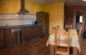 a kitchen with a table and a kitchen with a table and chairs at Apartamentos Vega Rodiles el llagar in Villaviciosa
