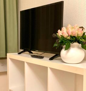 a television on a table with a vase of flowers at Hotel Arena Rooms - Berlin Mitte in Berlin